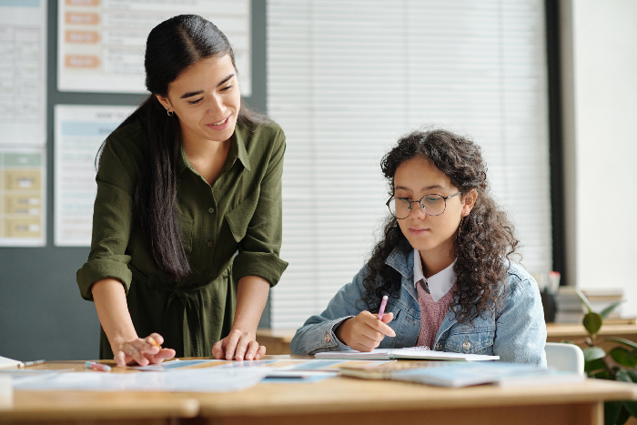 Experienced teacher mentoring a student in a focused discussion.