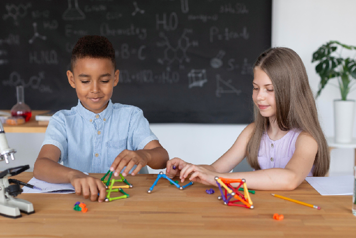 Elementary students collaborating to build geometric patterns using physical blocks inside a VPLS Seoni math lab.